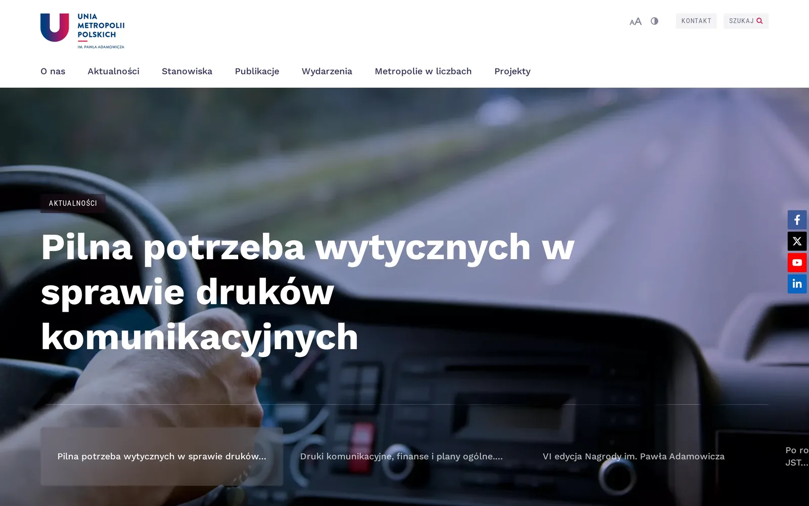 Strona główna Unii Metropolii Polskich na komputerze: logo, menu siedmiu działów i slider z wpisem „Pilna potrzeba wytycznych w sprawie druków komunikacyjnych” na zdjęciu kierownicy