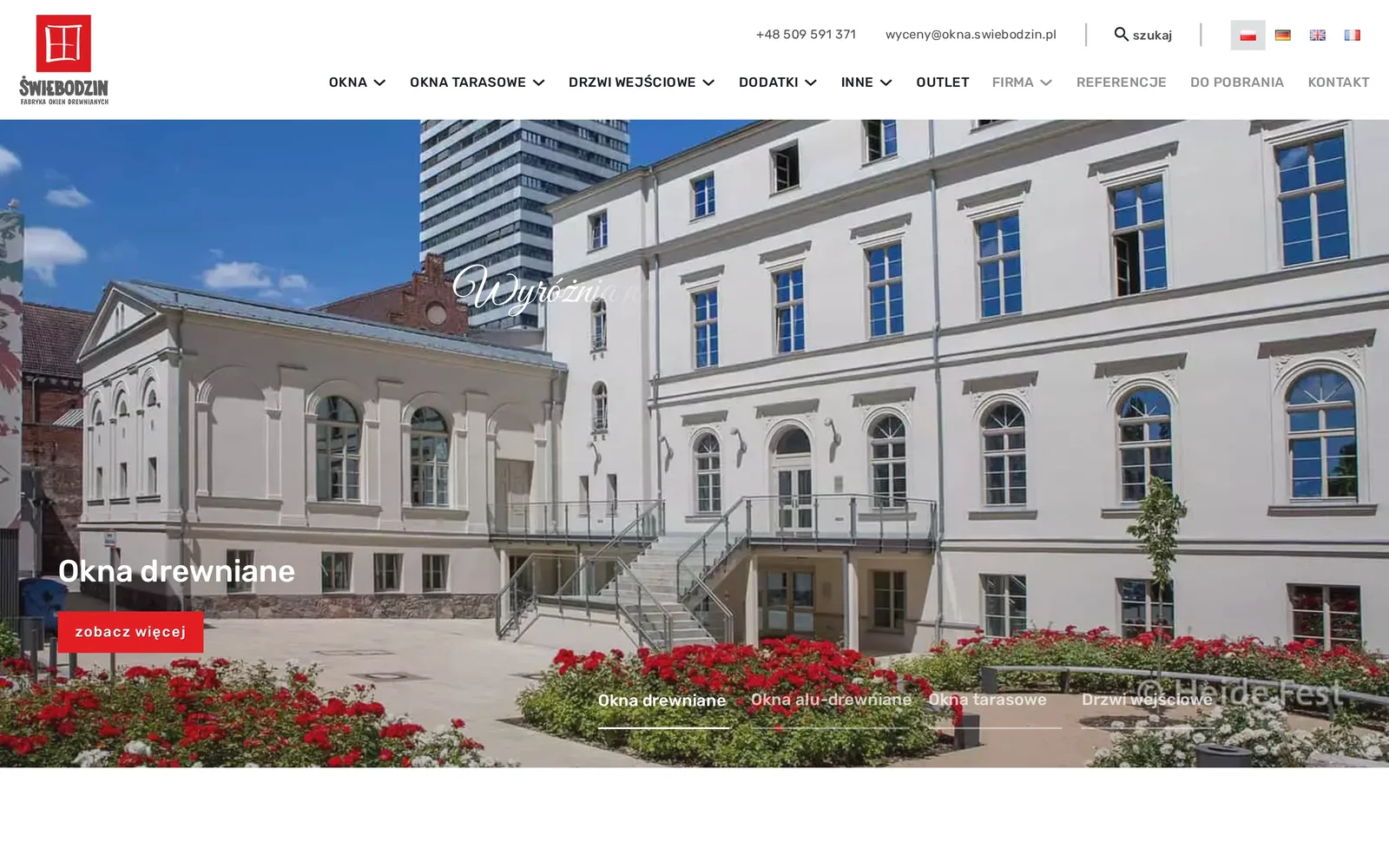 Strona główna Okna Świebodzin na komputerze: logo z oknem na czerwonym tle, menu z działami oferty, flagi czterech wersji językowych i slider ze zdjęciem kamienicy z drewnianymi oknami