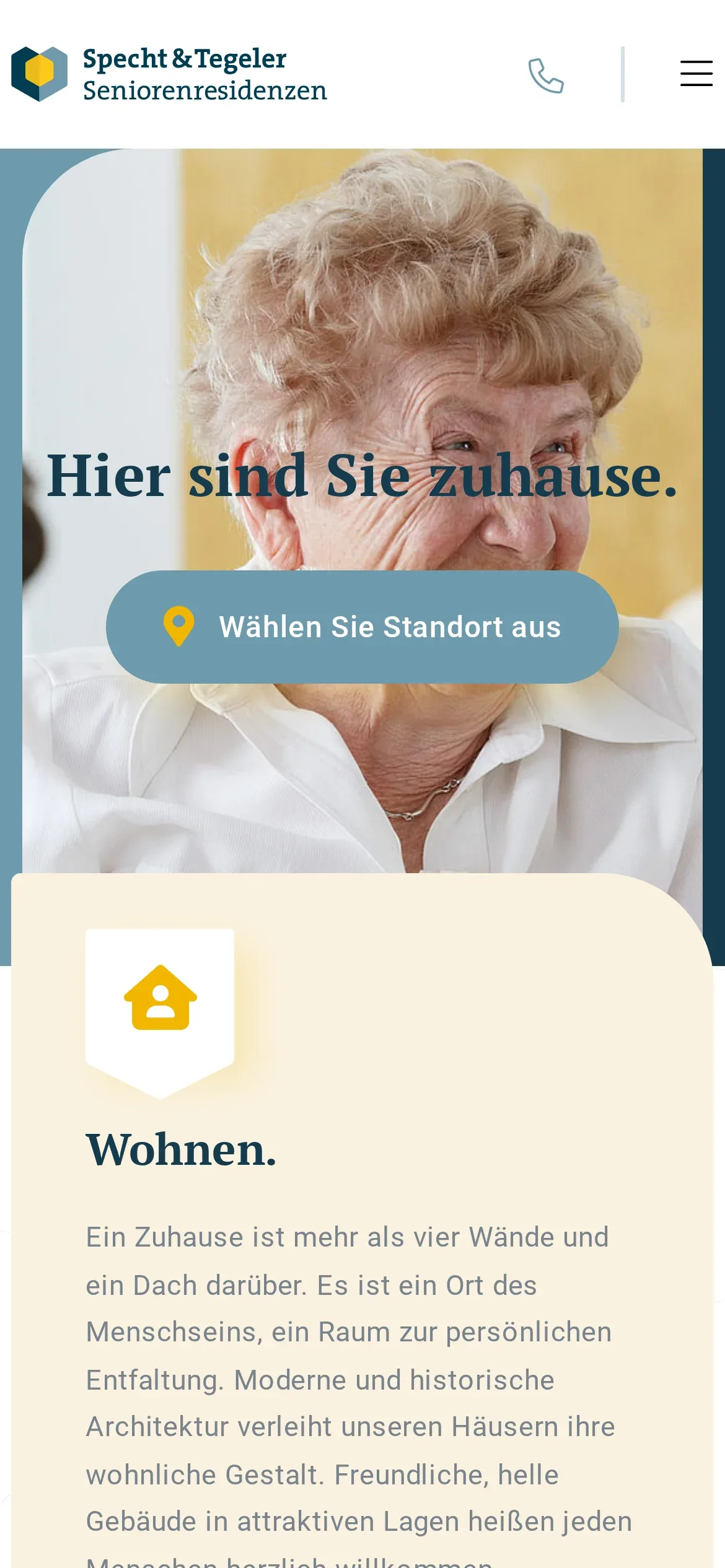 Strona główna Specht & Tegeler Seniorenresidenzen na telefonie: logo, ikona telefonu i przycisk menu, zdjęcie z hasłem „Hier sind Sie zuhause.” i przyciskiem „Wählen Sie Standort aus”, pod nim początek pola „Wohnen.”